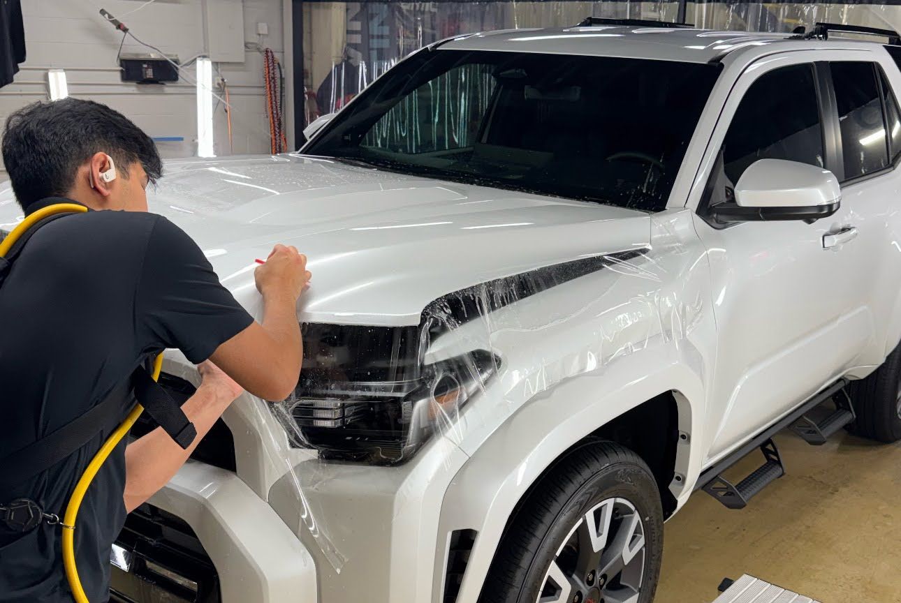 Worker polishing the front of a white SUV in a garage