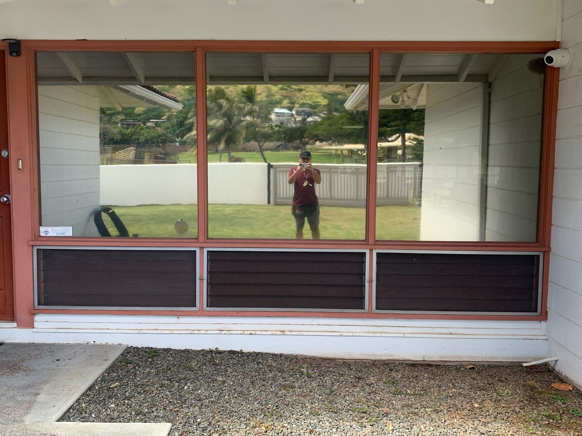 Front view of a screened porch with large windows and a gravel path in front
