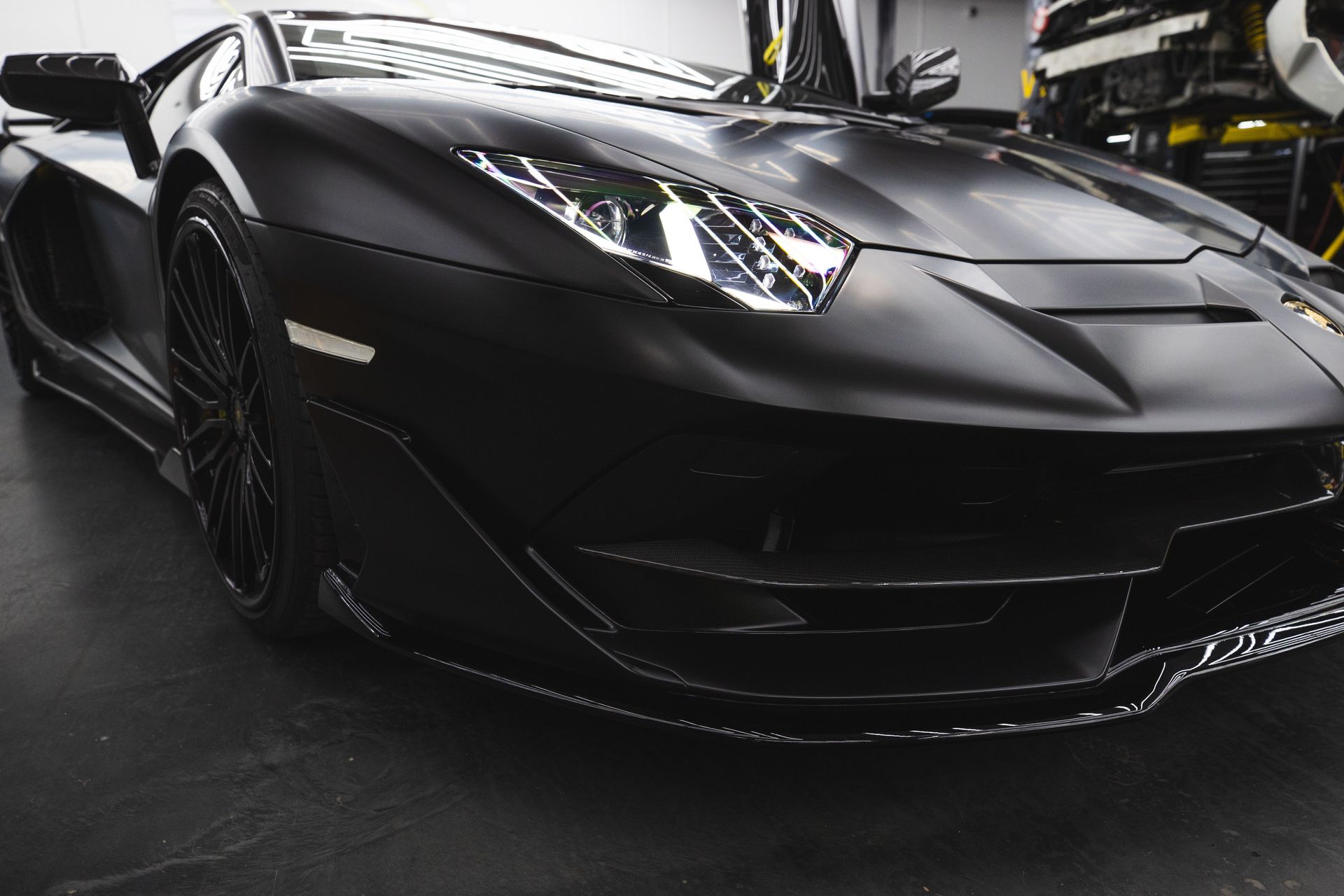 Matte black sports car in a garage, front view with sleek, low profile styling
