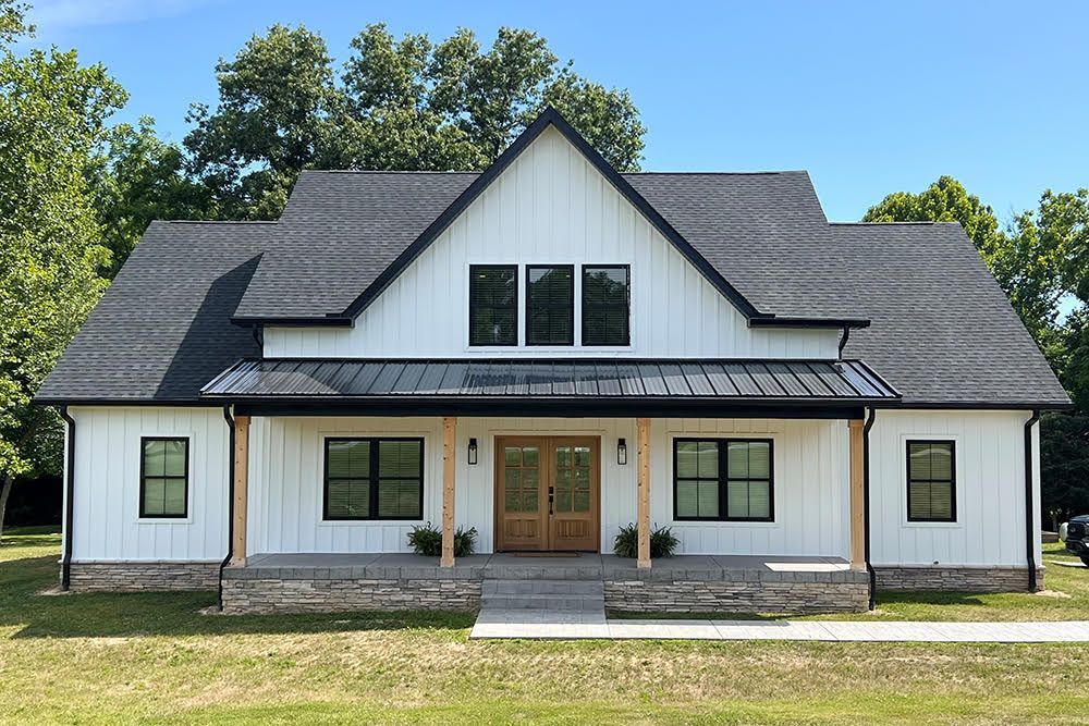 White farmhouse with black trim, gray roof, and front porch.