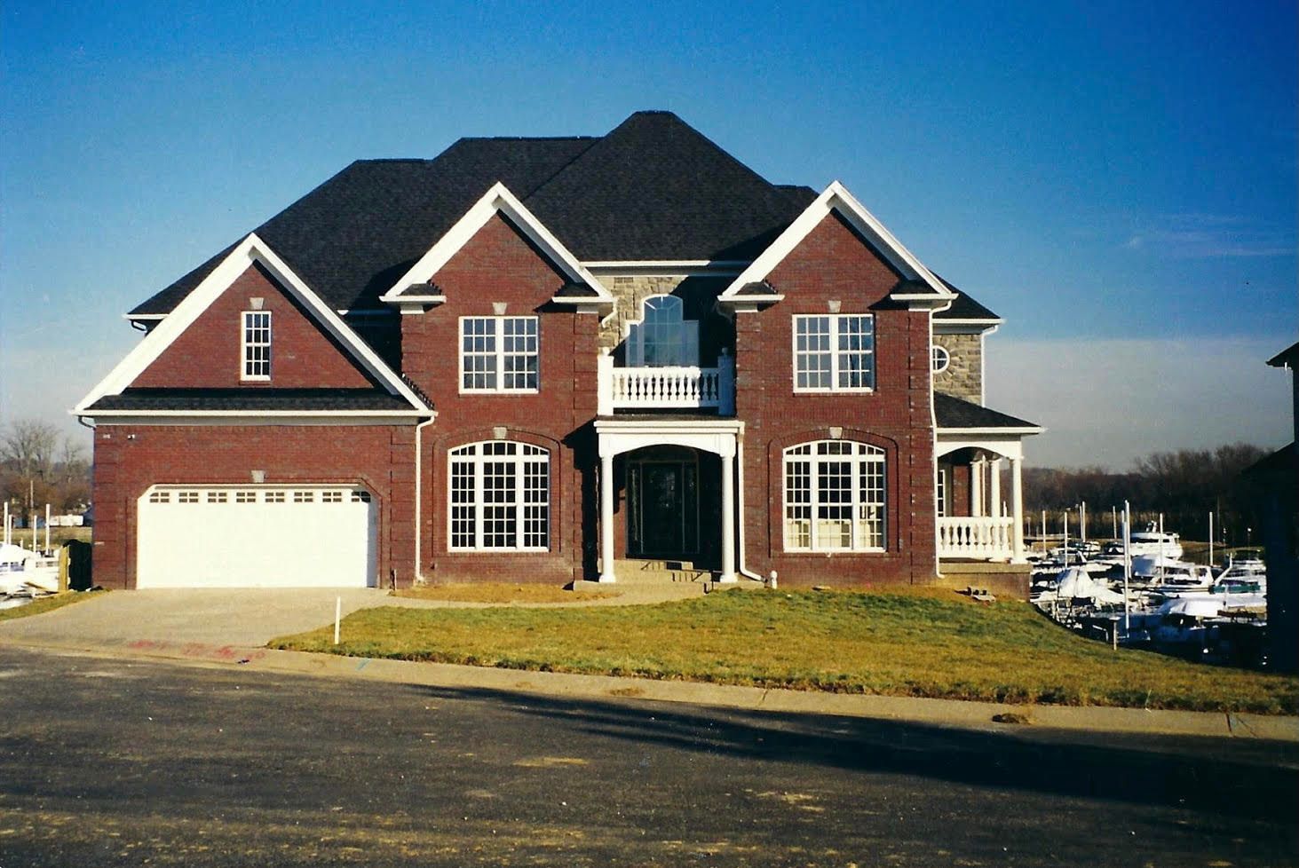 Two-story brick house with white trim, dark roof, and arched windows. Garage on the left.