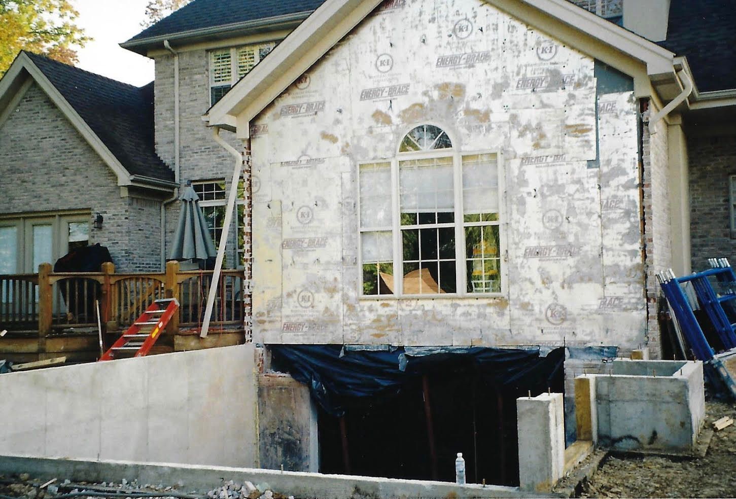 House undergoing renovation with exposed framing and a large window.