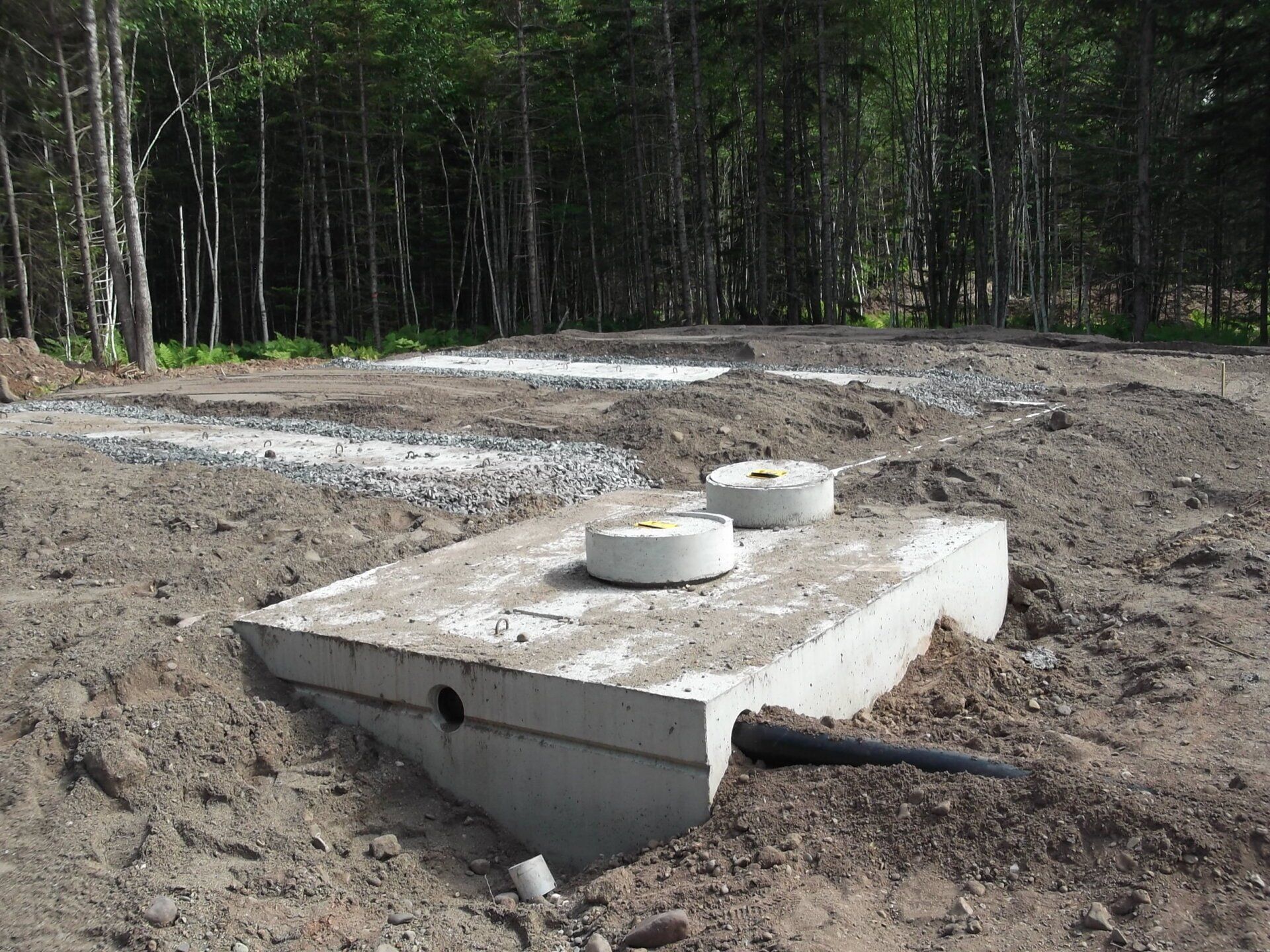 A septic tank is sitting in the middle of a dirt field.