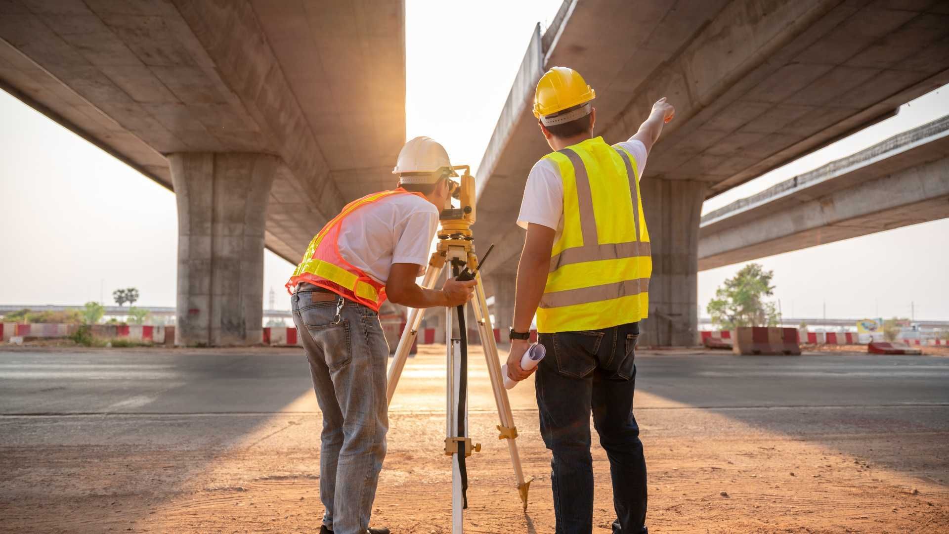 Two construction workers are working on a bridge.