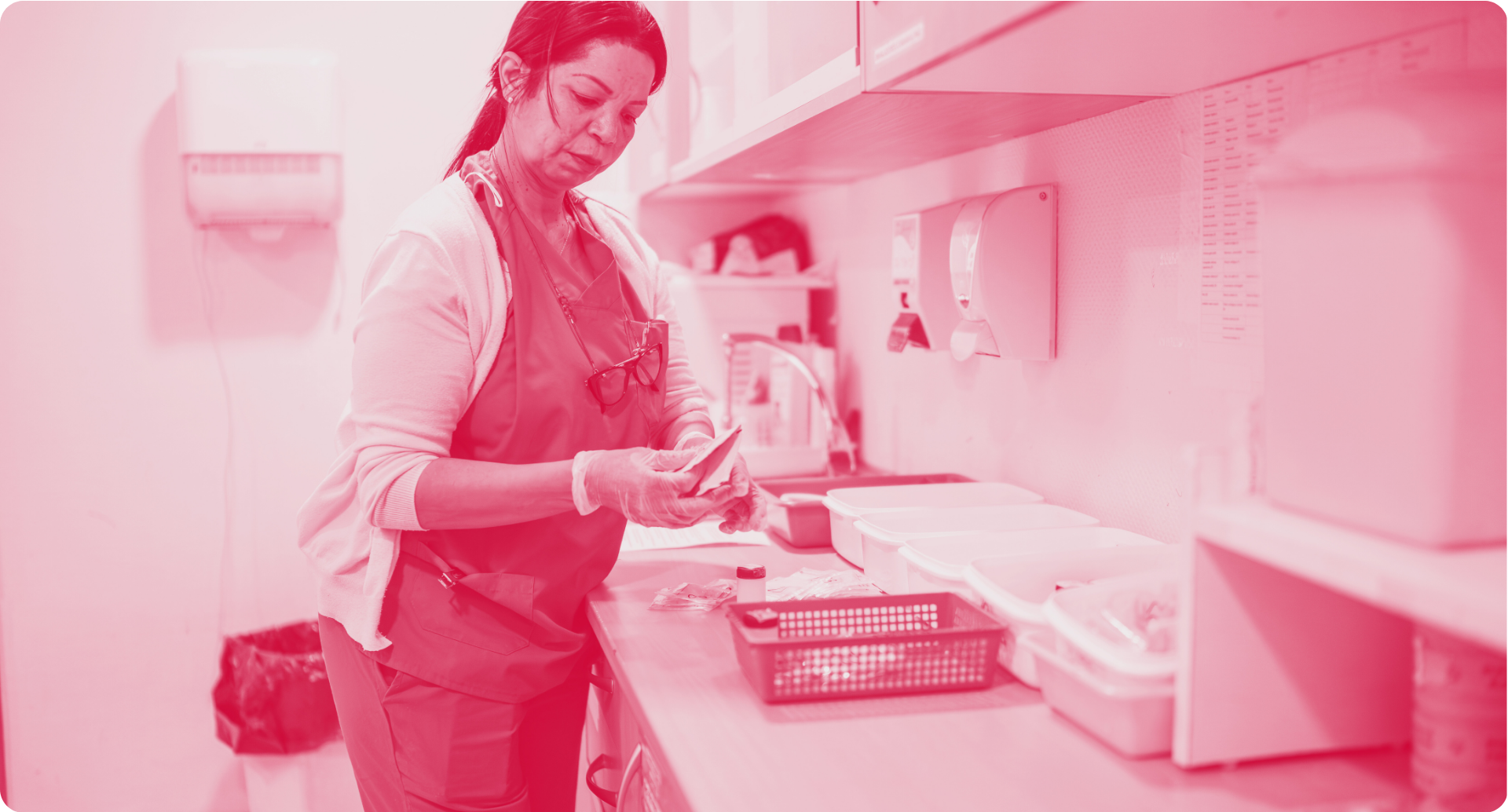 Person wearing apron and gloves in a medical setting, preparing items on a counter.