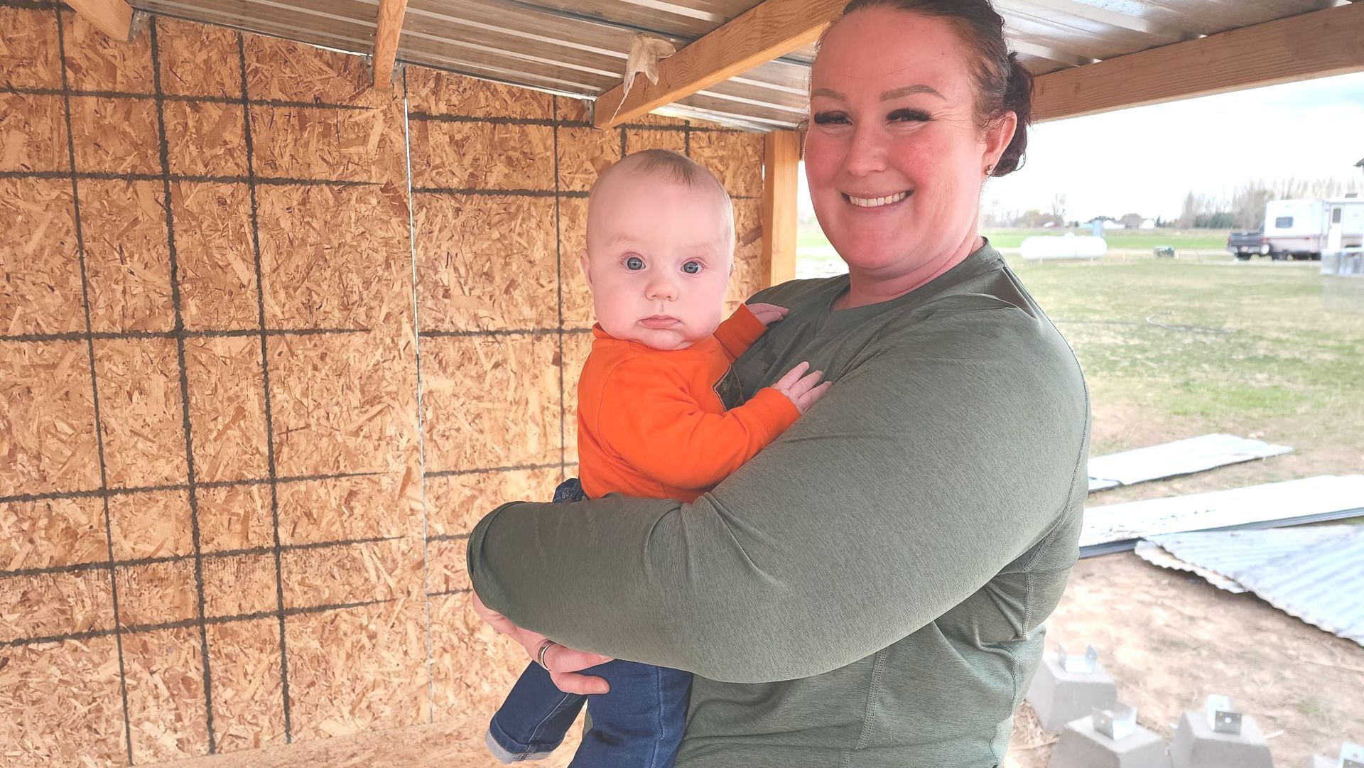 A woman is holding a baby in her arms and smiling.