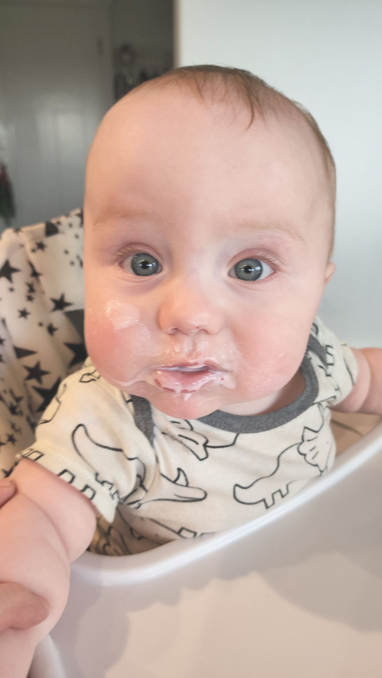 A baby is sitting in a high chair with food on his face.