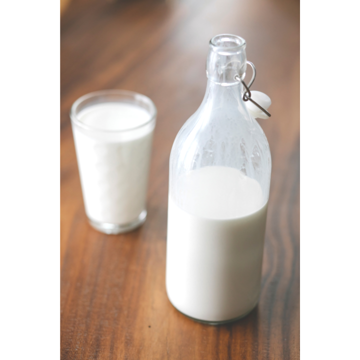 A glass and bottle of milk on a wooden table