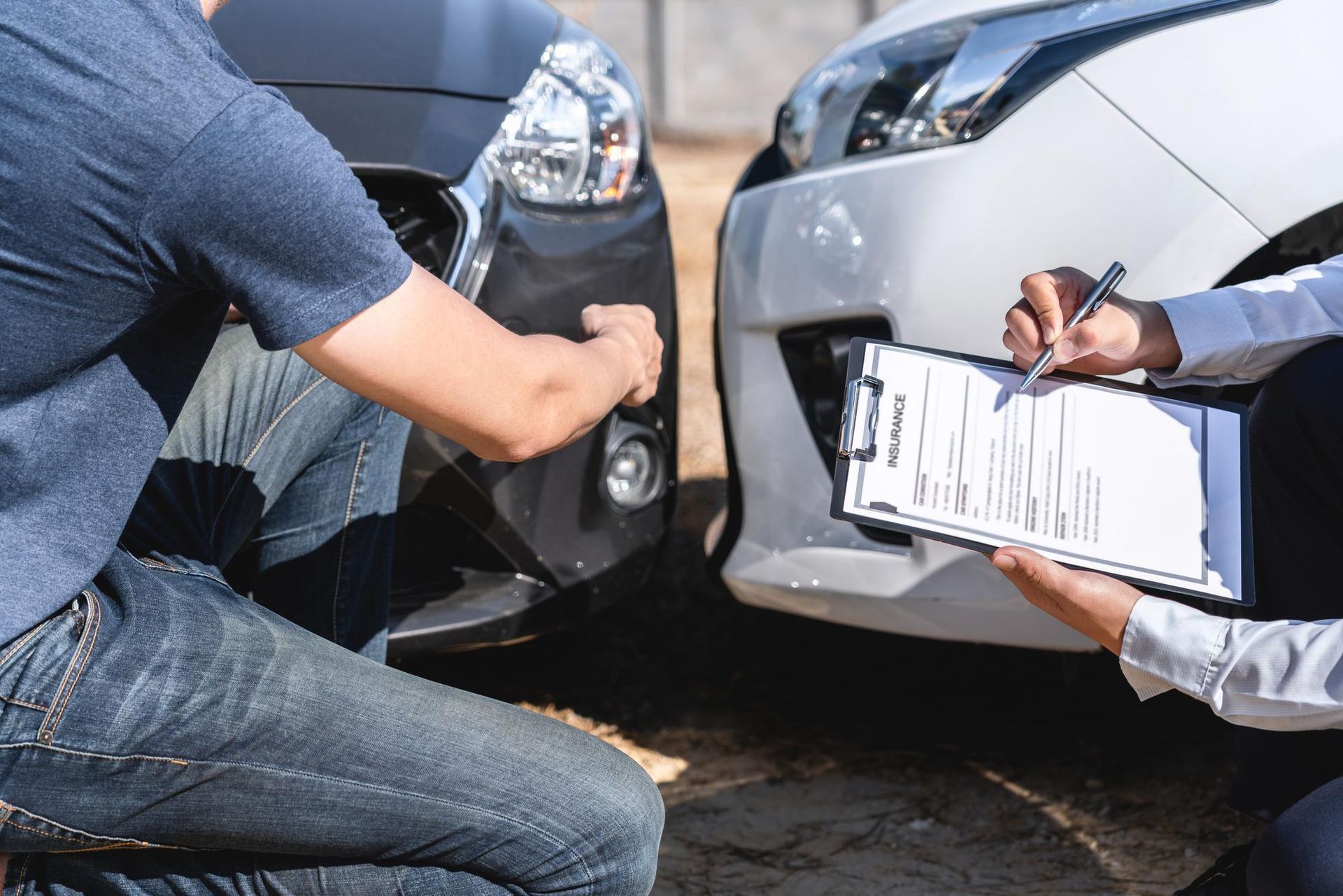 Two cars in a minor collision while a person fills out accident paperwork beside them