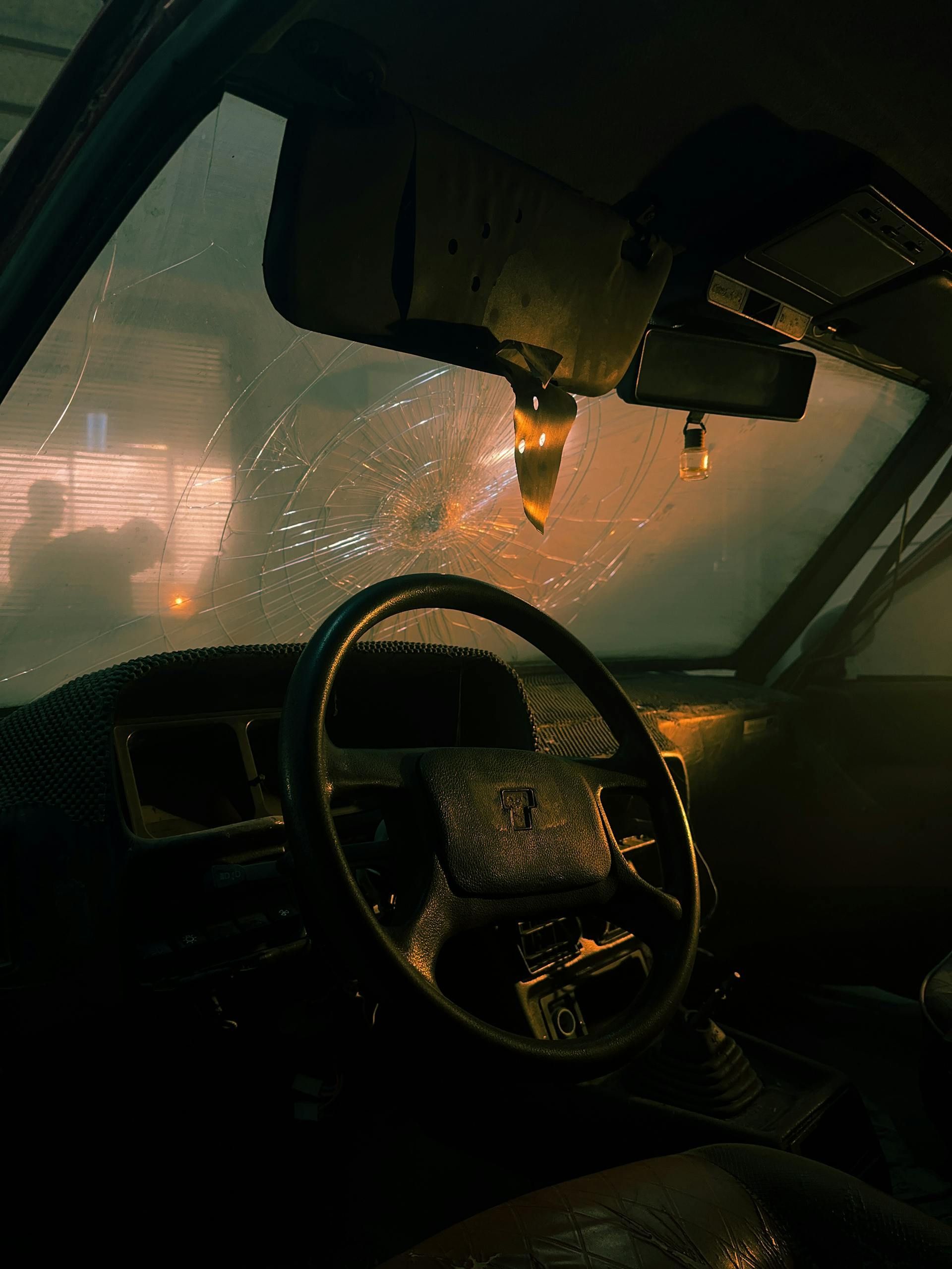Car interior at night in heavy rain, with windshield wipers and orange streetlights glowing through the glass