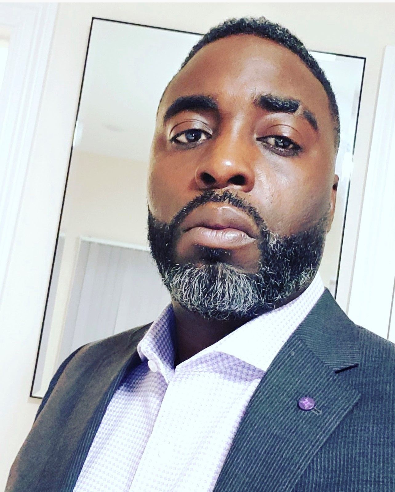 A man with a beard is wearing a suit and tie