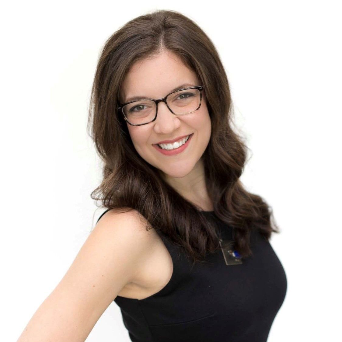 A woman wearing glasses and a black tank top is smiling for the camera.