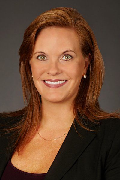 A woman with long red hair is smiling for the camera