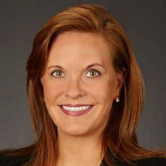 A woman with red hair and green eyes is smiling for the camera.