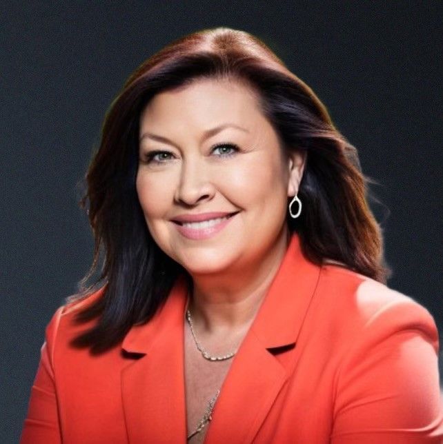 A woman wearing a red jacket and earrings smiles for the camera