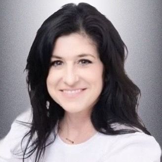 A woman with long black hair is wearing a white shirt and smiling.