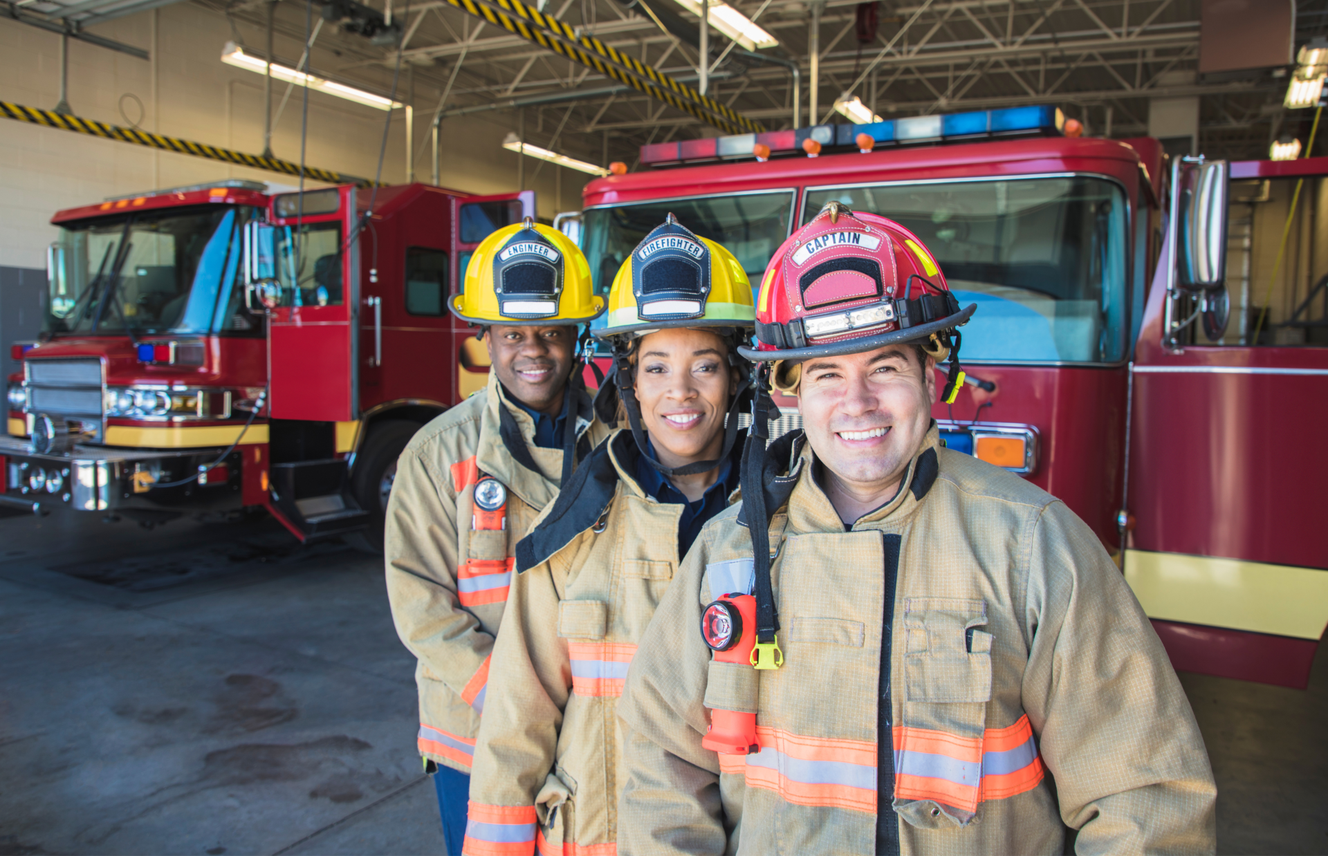 Three firefighters are posing for a picture in front of a fire truck.