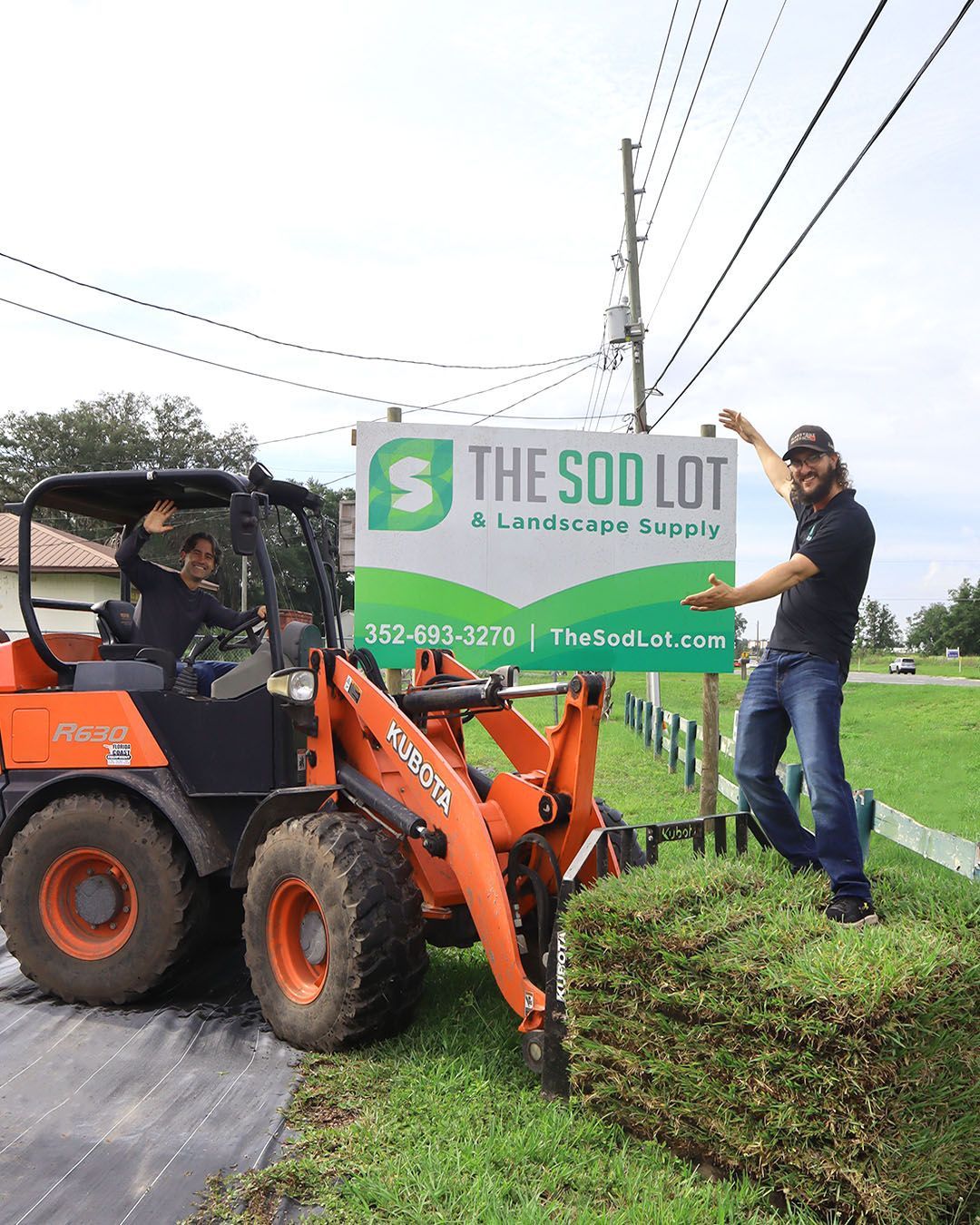 Person rolling out dark sod over a garden bed beside green grass