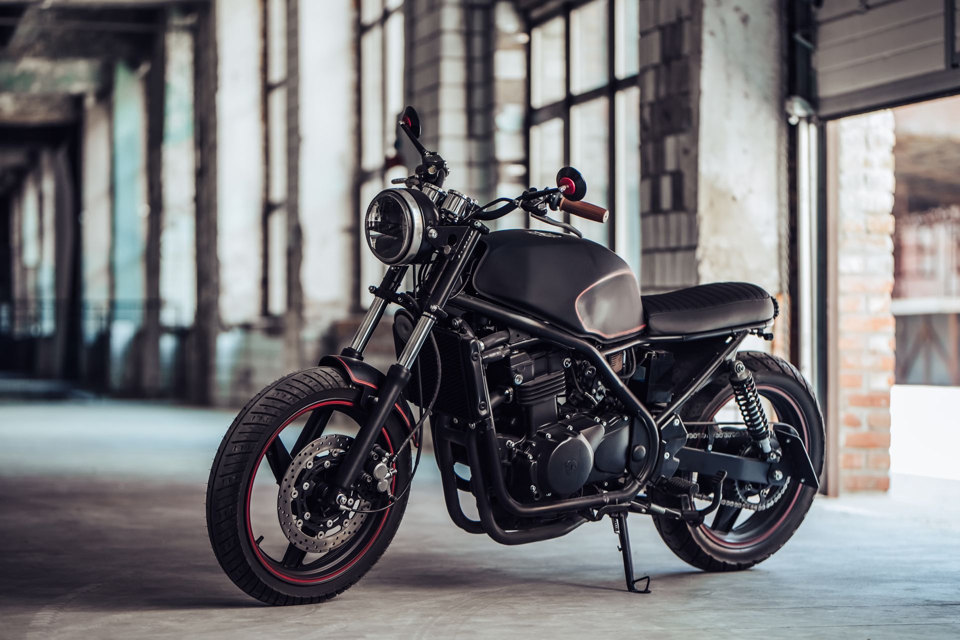 Black custom motorcycle parked in an industrial warehouse interior.