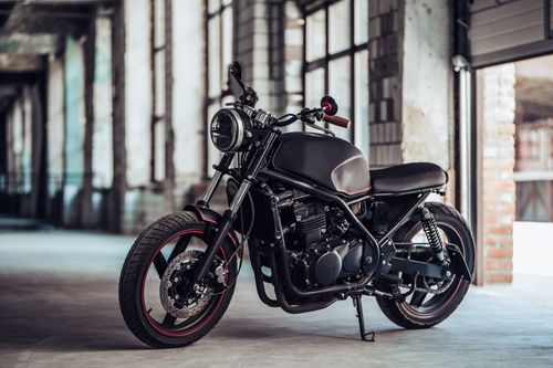 Black custom motorcycle parked in an industrial warehouse interior.