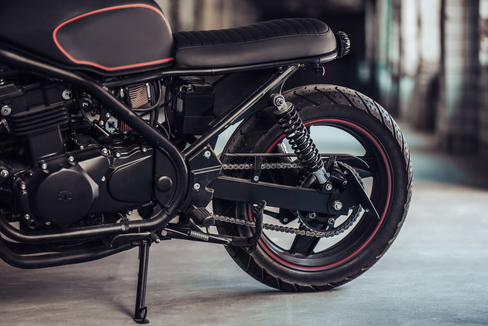 Black custom motorcycle with red accents parked indoors on a side stand.