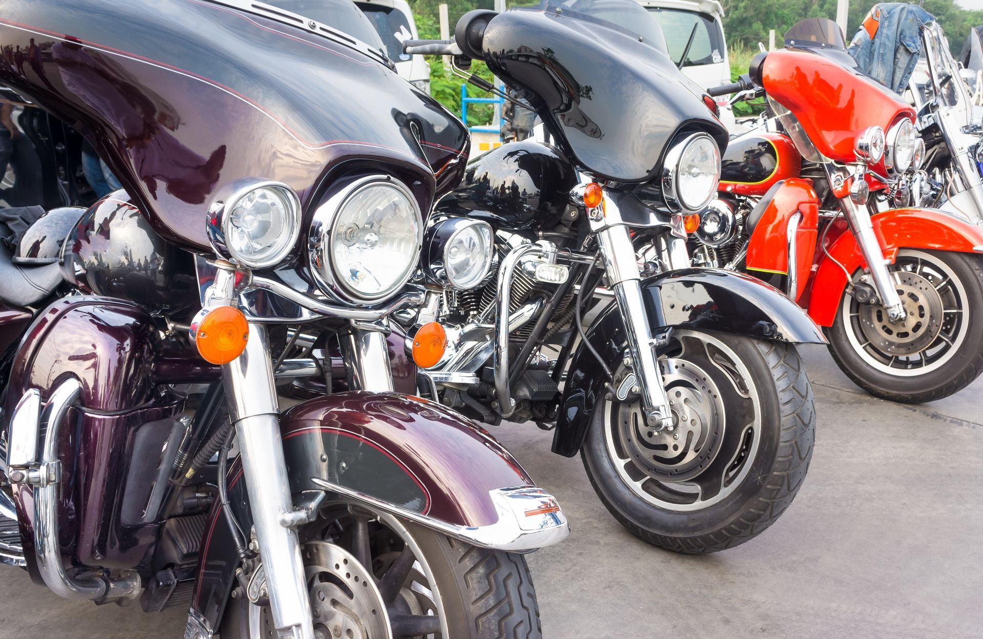 Row of parked touring motorcycles in black, gray, and red on a paved lot.