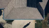 An aerial view of a house with a shadow of a person on the driveway.