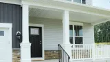 A white house with a black door and a white porch.