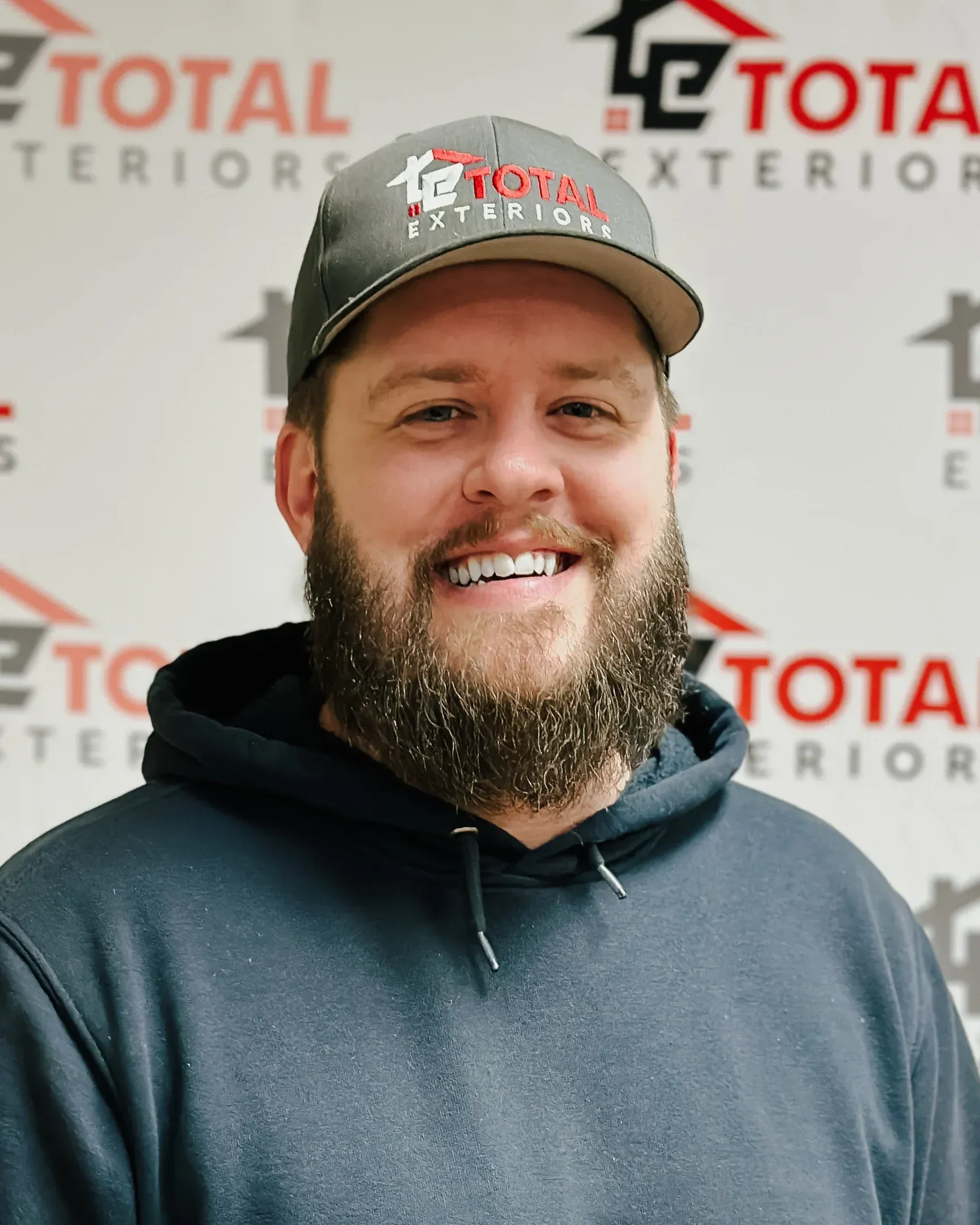 A man with a beard is wearing a hat and a hoodie.