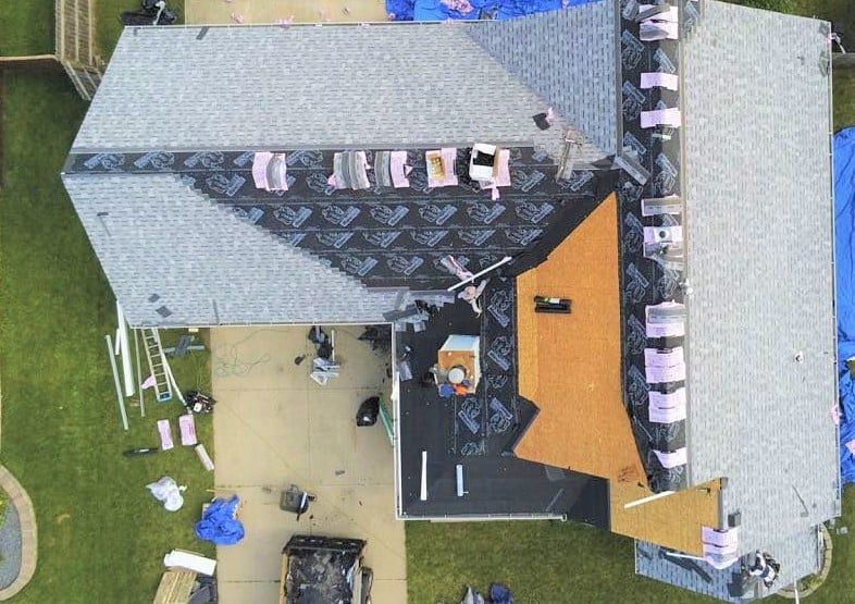 An aerial view of a house under construction with a roof being installed.