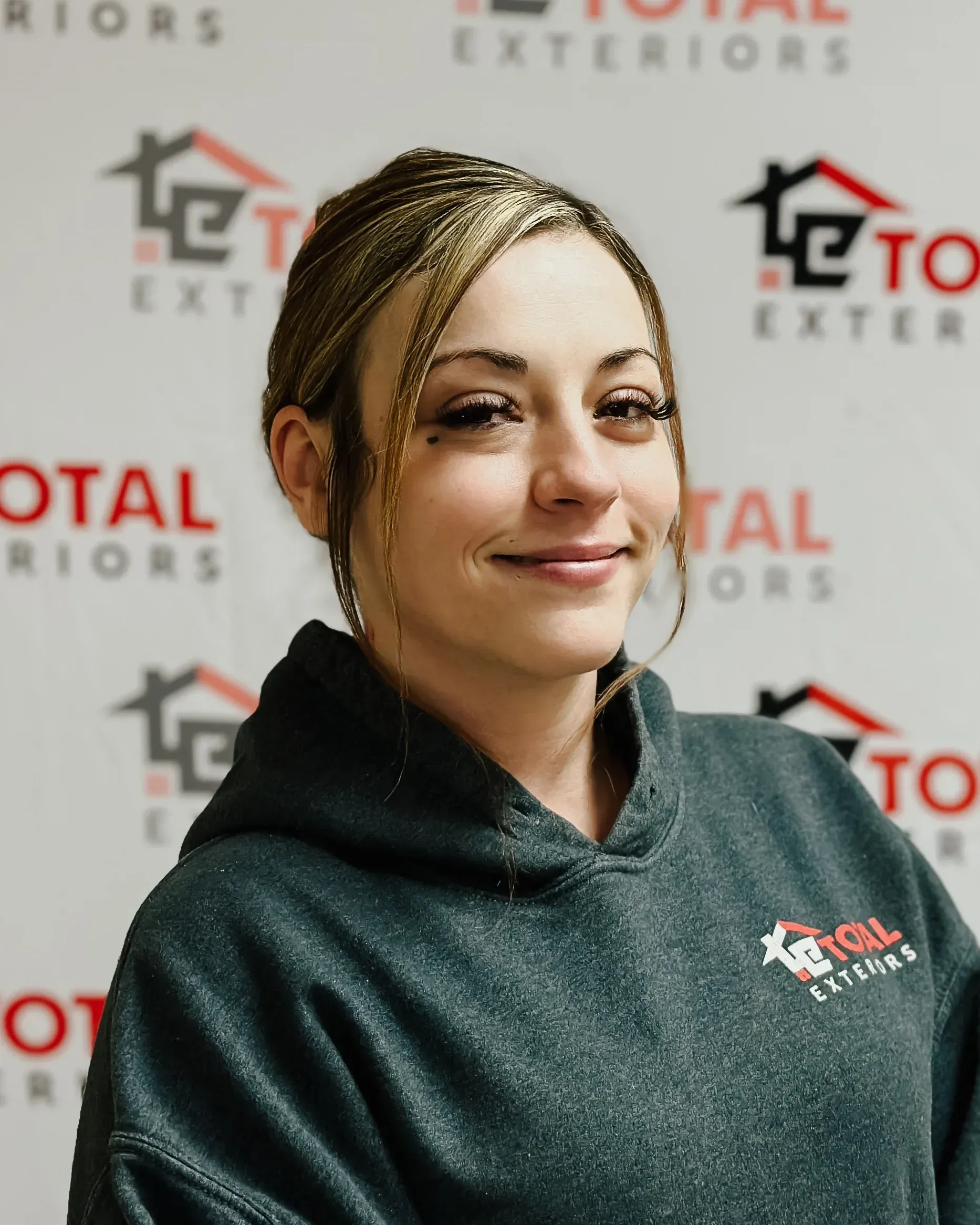 A woman wearing a total exteriors hoodie smiles for the camera