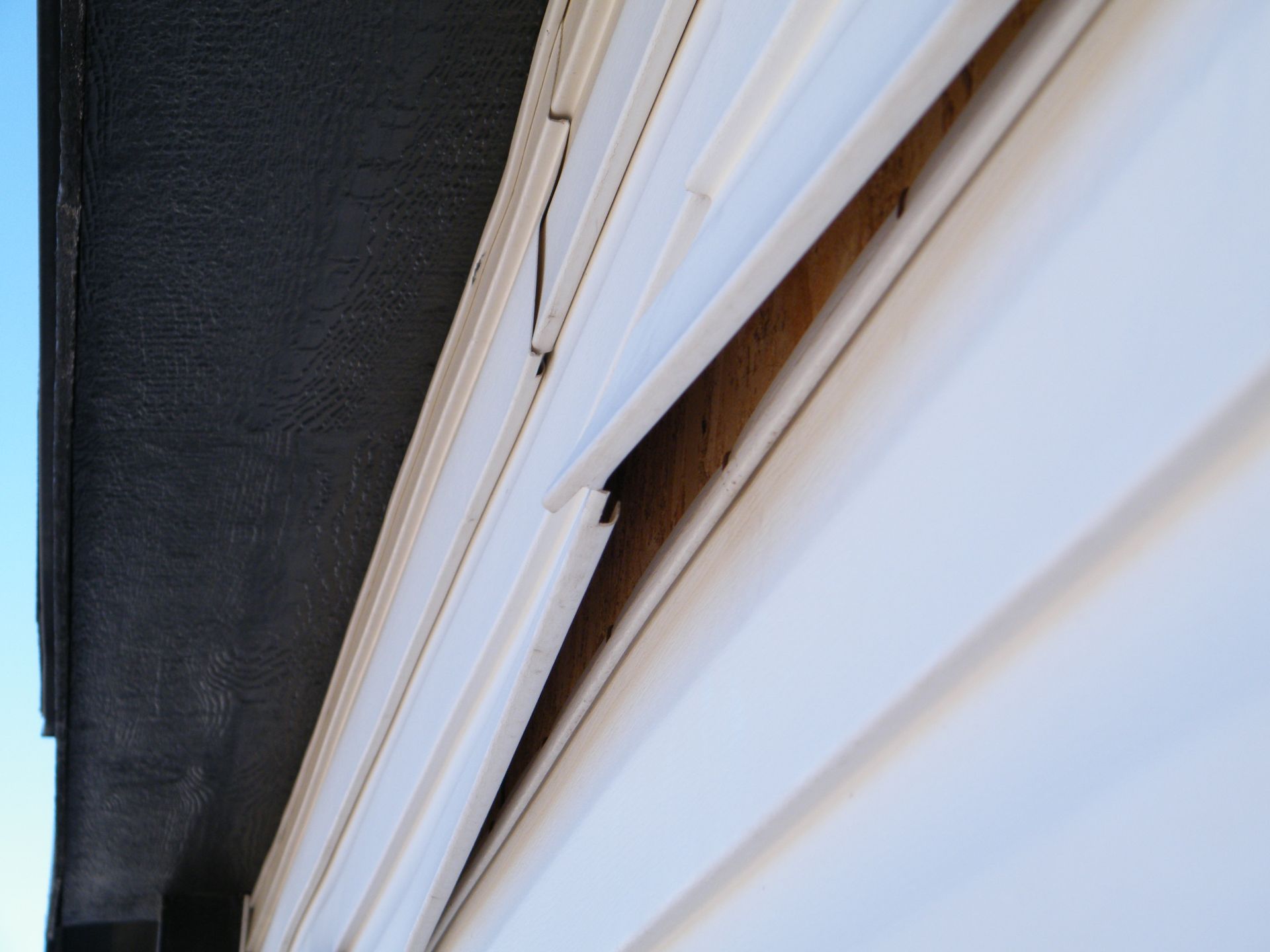 White siding damaged and pulled away from the wall, revealing wood underneath.