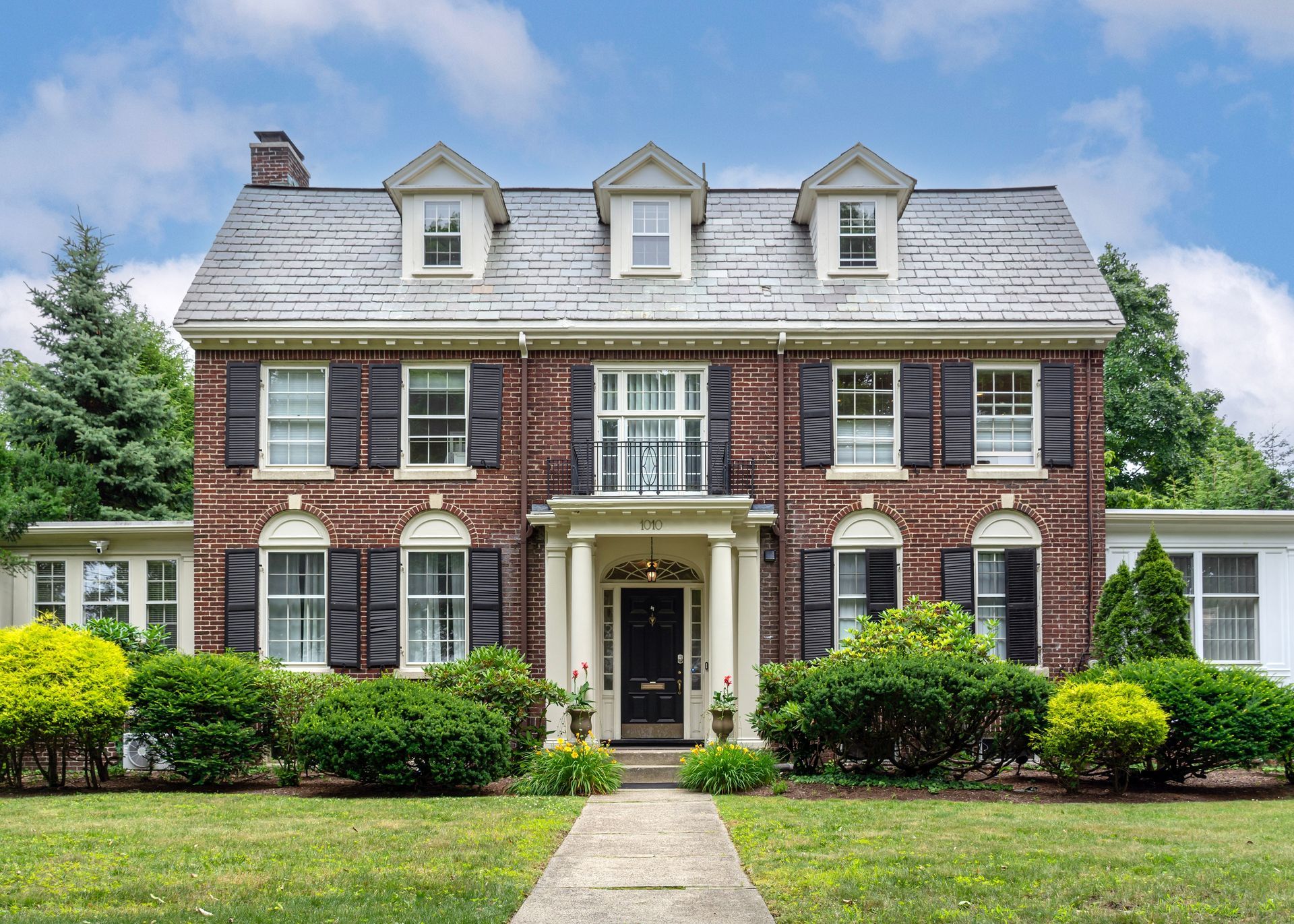 A large brick house with a slate roof and black shutters
