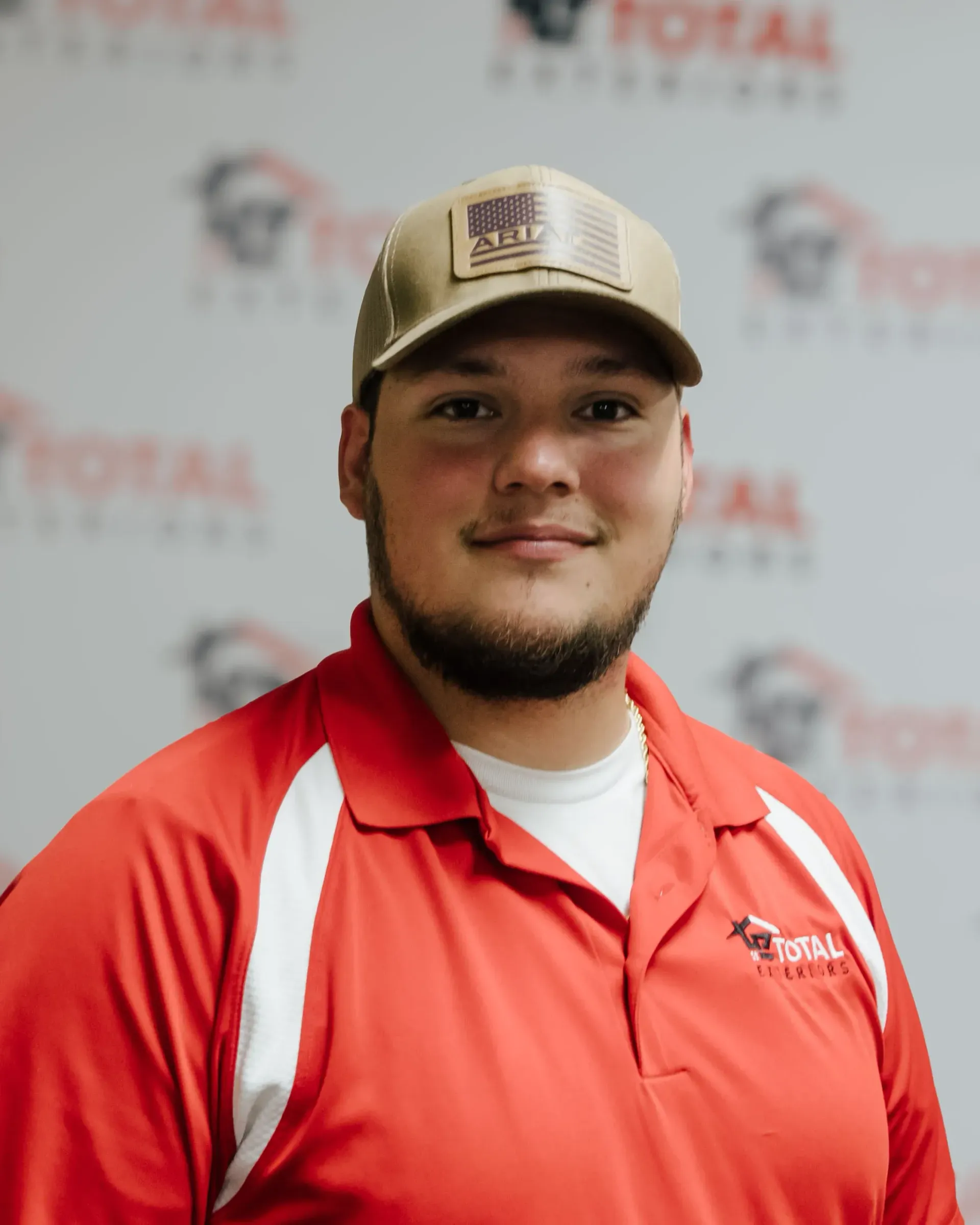 A man wearing a hat and a red shirt is smiling for the camera.
