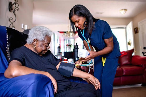 Caregiver checking patient's blood pressure with stethoscope and cuff in a home setting.