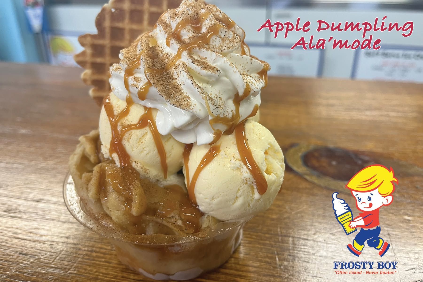 Apple dumpling topped with whipped cream and caramel drizzle in a glass dish on a table.