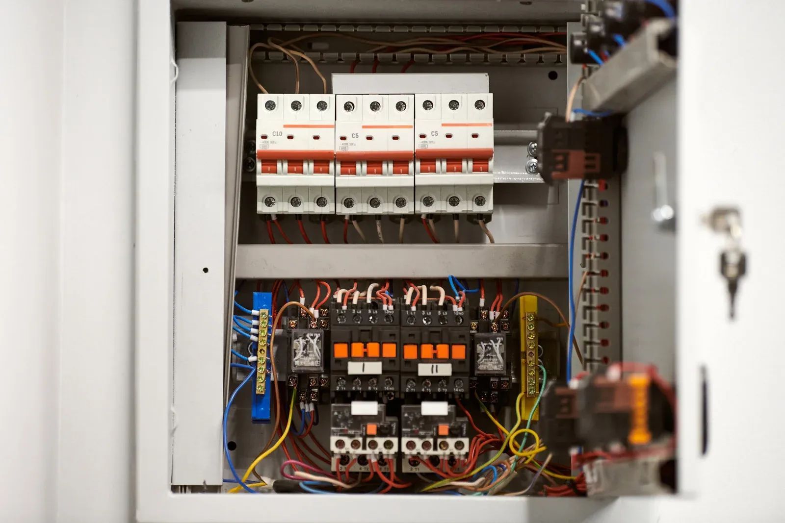 Open electrical control panel with circuit breakers, relays, and wiring inside a metal cabinet