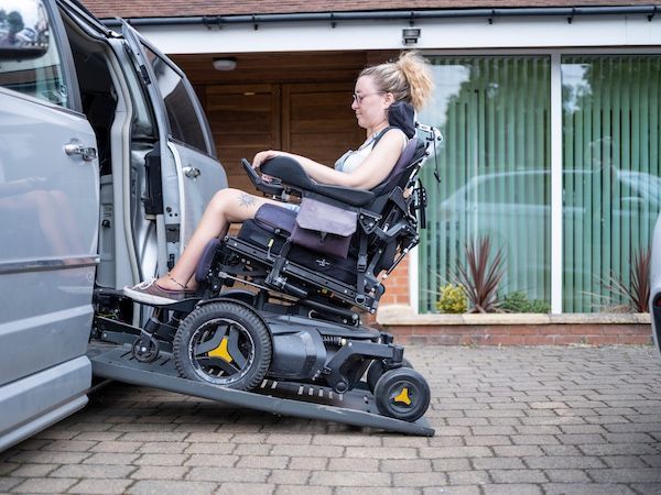 A lady in a wheelchair enters the transportation van