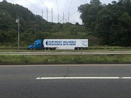 Blue semi-truck on highway, text says