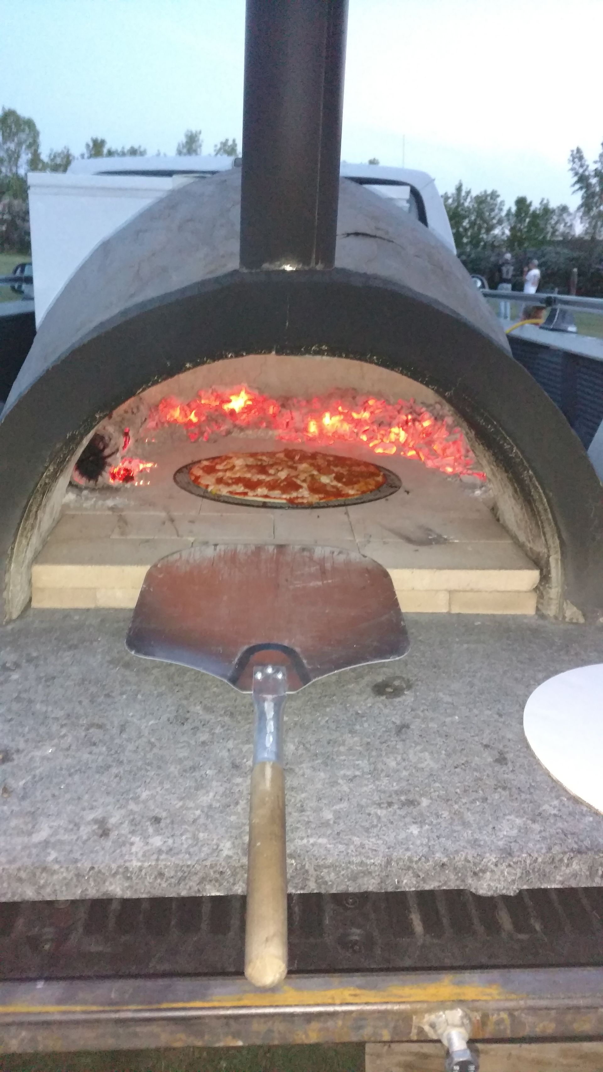 Wood-fired pizza oven with a glowing fire and a pizza baking inside