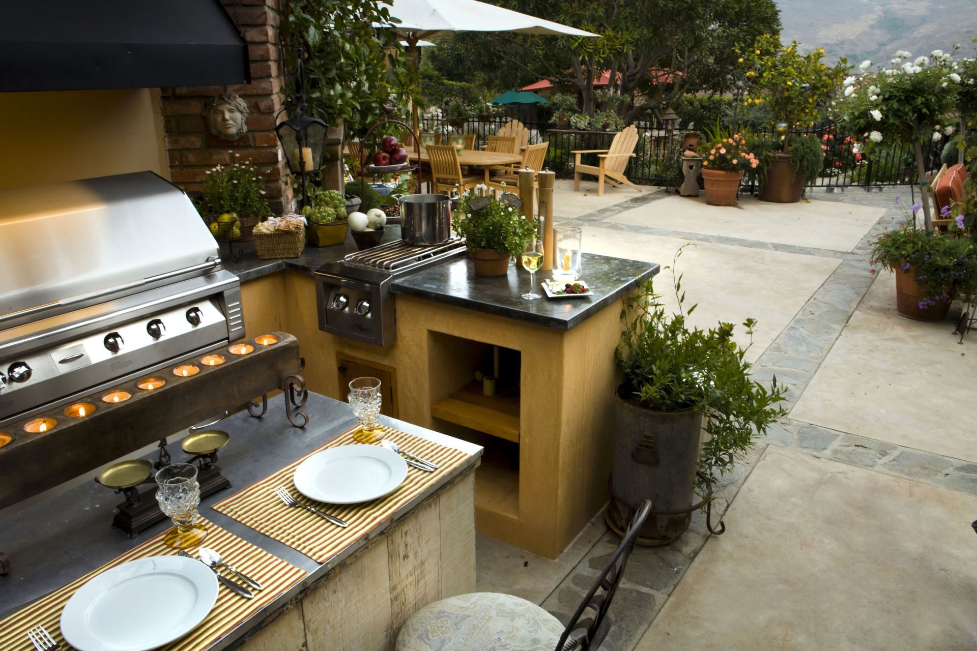 Outdoor patio with grill, dining table, and potted plants beside a walkway