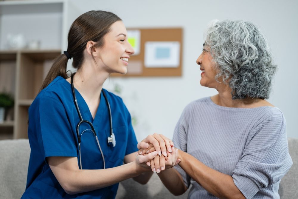 A nurse is holding the hand of an elderly woman.