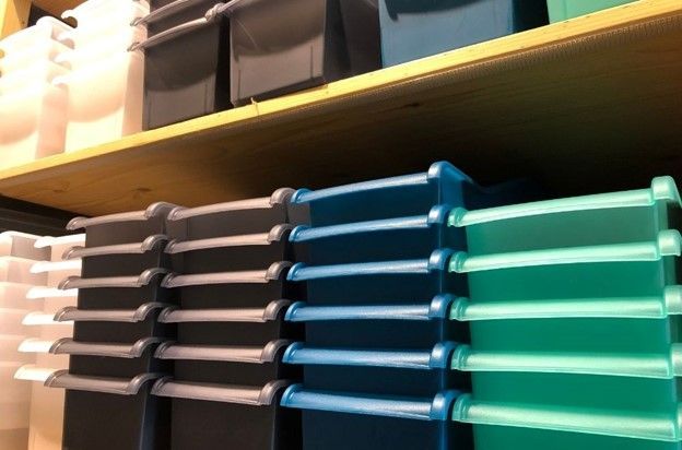 A bunch of plastic bins are stacked on top of each other on a shelf.