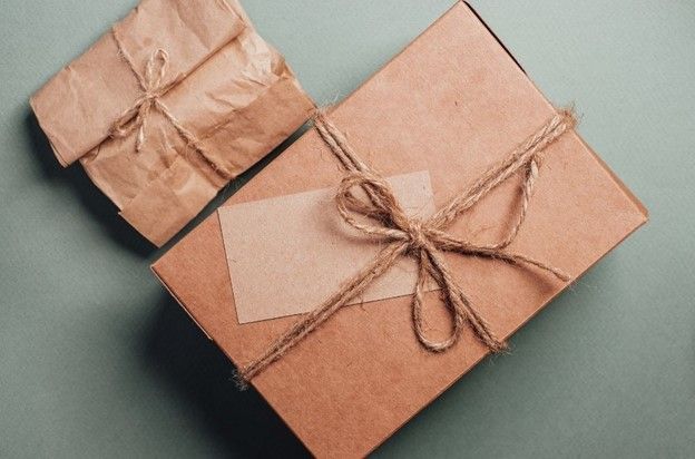 Two boxes wrapped in brown paper and tied with string on a table.