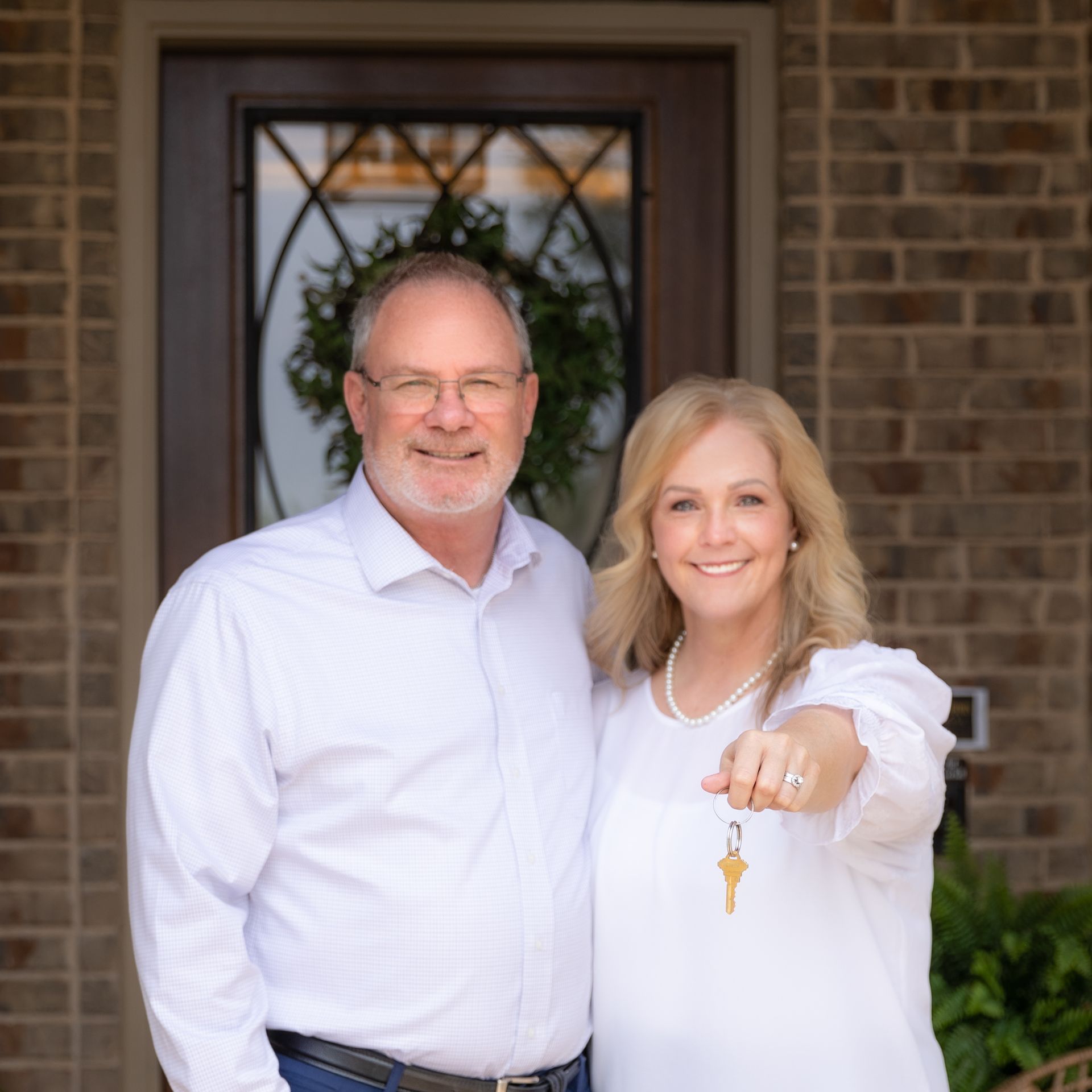 A man and a woman are posing for a picture in front of a brick building.