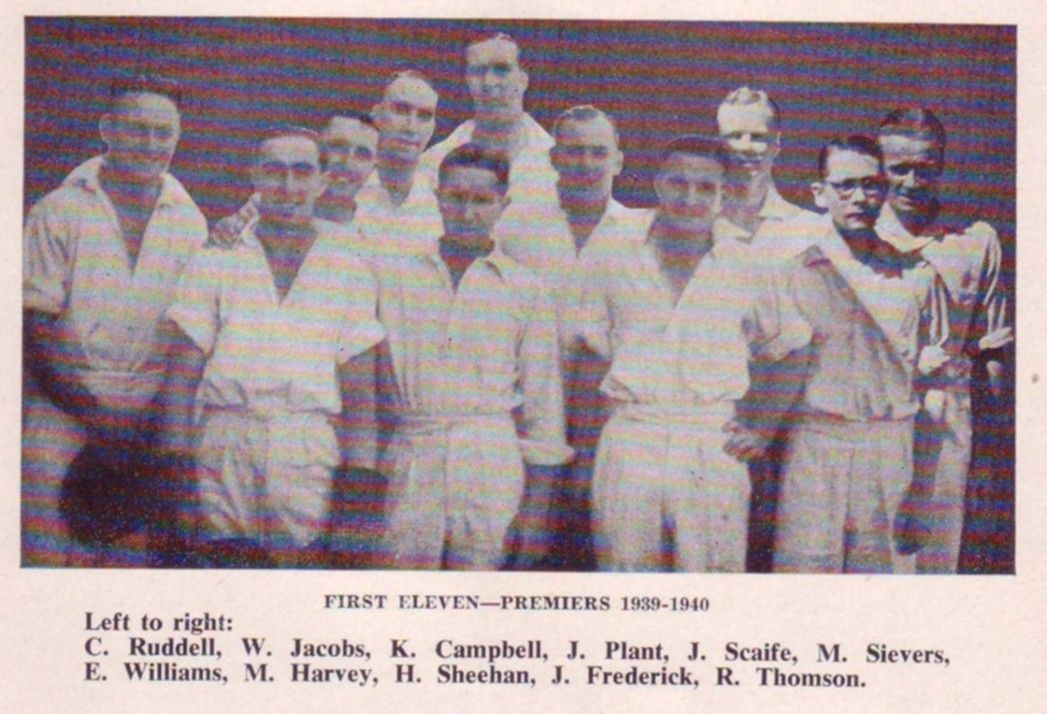 Black-and-white group portrait of eight people in white uniforms standing in two rows outdoors.