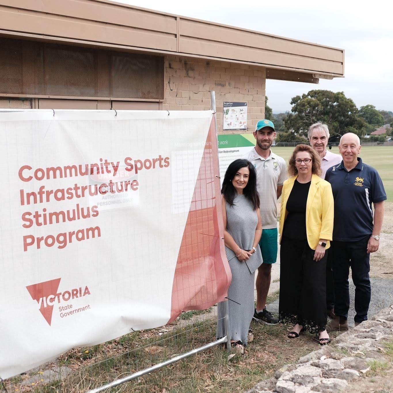 People standing beside a banner reading “Community Sports Infrastructure Stimulus Program”