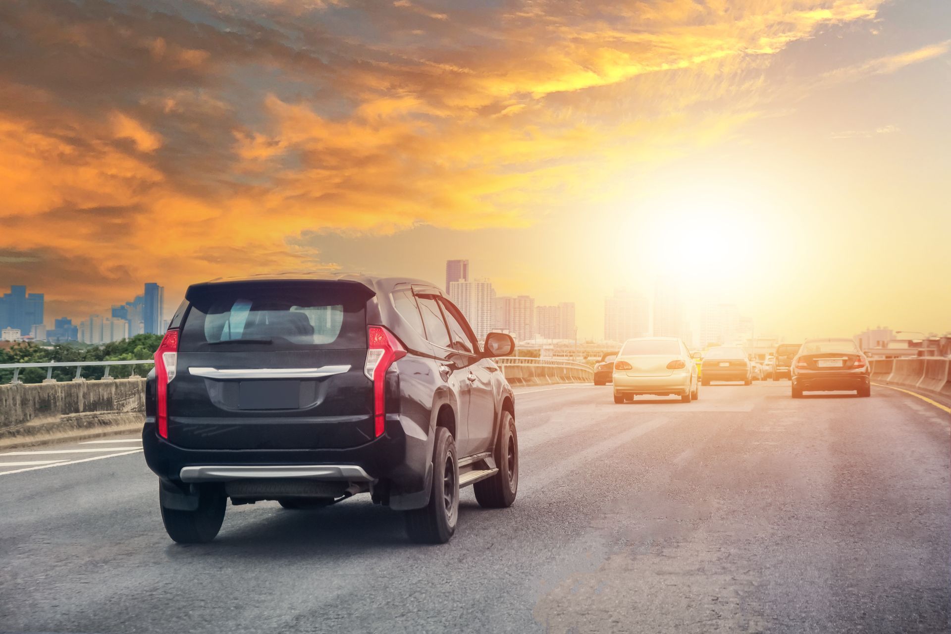A car is driving down a highway at sunset.