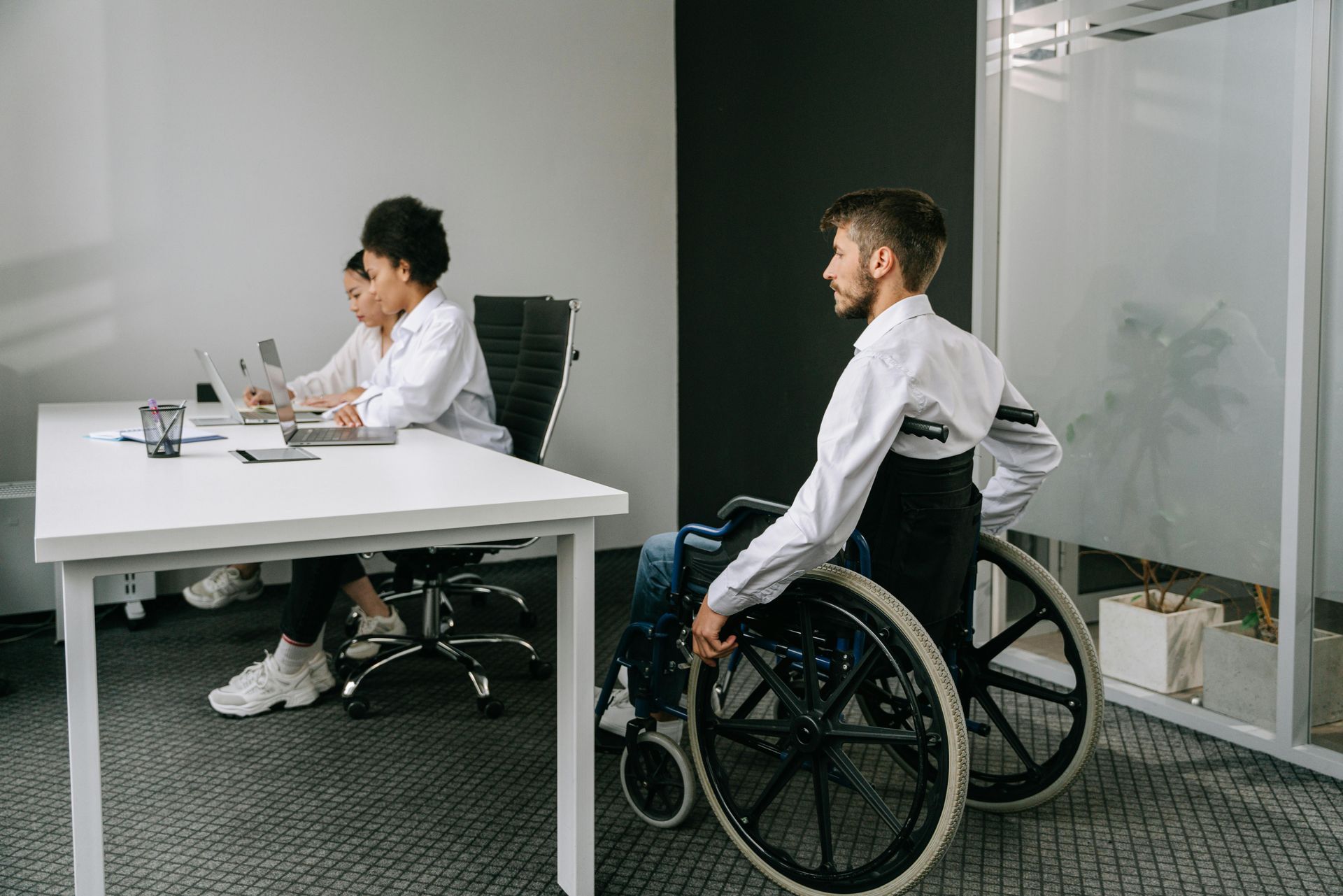 A man in a wheelchair is sitting at a table with two other people.