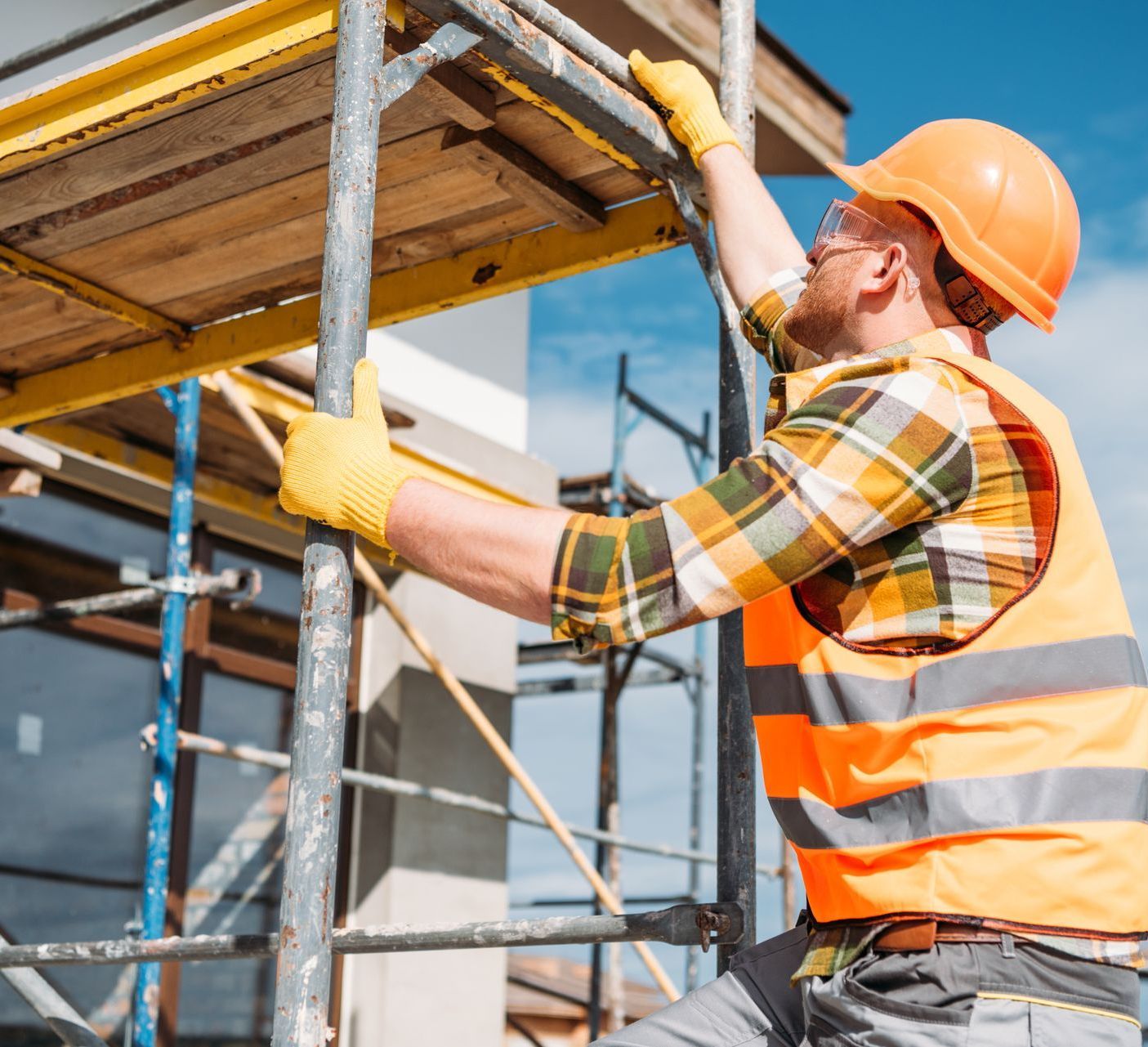 the builder builder climbing on scaffolding at construction site - demonstrating scaffolding safety